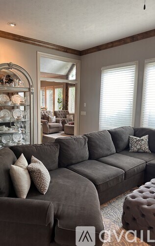 A living room with a grey sofa and a glass display cabinet.