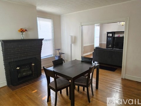 A black table with four chairs sits in a room with a fireplace.