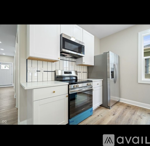 A kitchen with white cabinets and a stainless steel refrigerator.