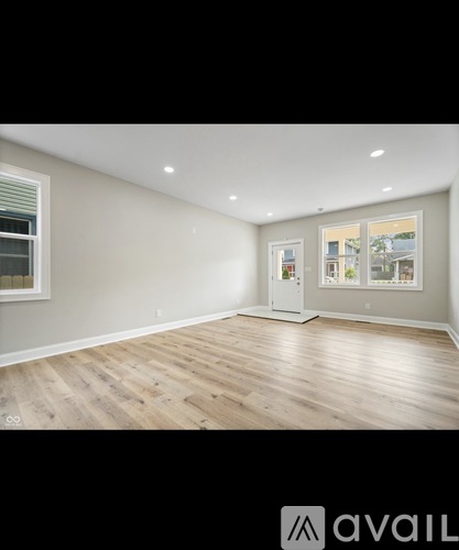 A spacious room with wooden flooring and a large window.