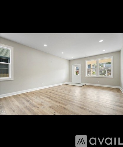 A spacious room with wooden flooring and a large window.