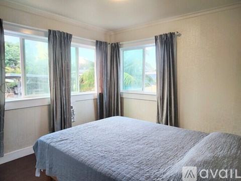 A bedroom with a large bed and a window with curtains.