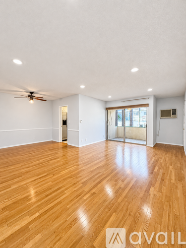 A spacious room with wooden flooring and a ceiling fan.