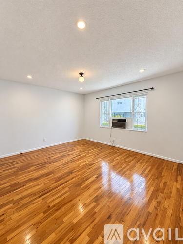 A room with wooden flooring and a window with blinds.
