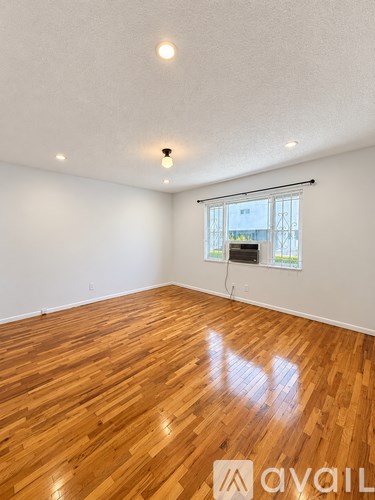 A room with wooden flooring and a window with blinds.
