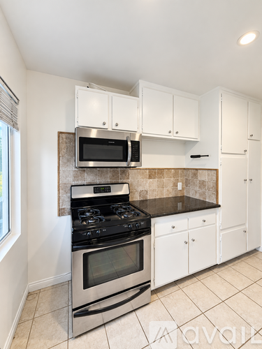 A kitchen with white cabinets and a black stove top oven.