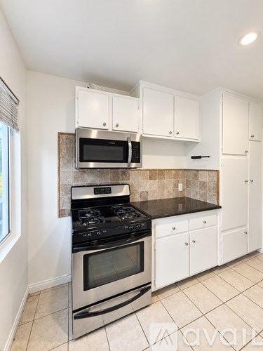 A kitchen with white cabinets and a black stove top oven.