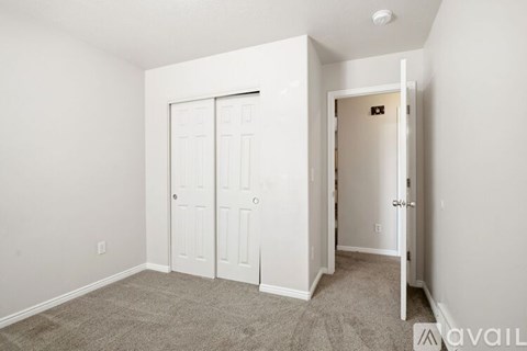 A bedroom with a white door and a carpeted floor.