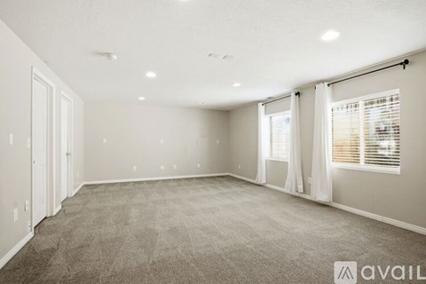 A spacious room with carpeted floor and white walls.