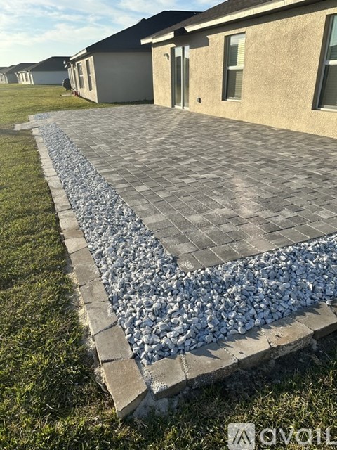 A cobblestone walkway leads to a house.