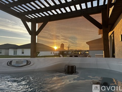A hot tub is in the foreground of a sunset scene.