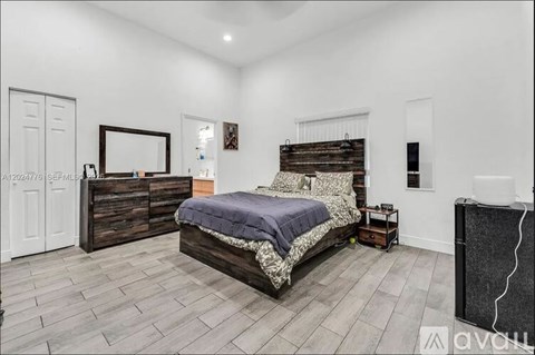 A bedroom with a large bed, a wooden dresser, and a mirror on the wall.