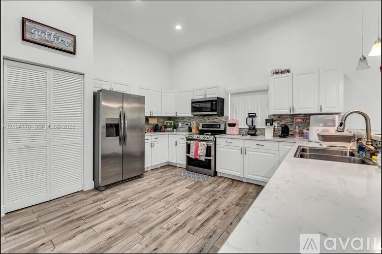 A kitchen with white cabinets and a wooden floor.