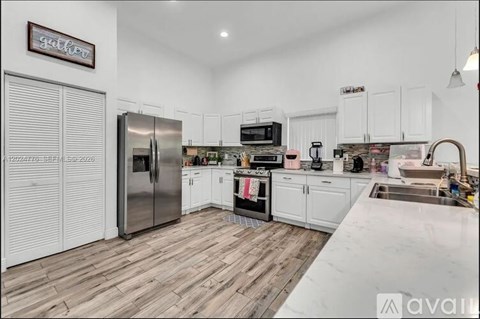 A kitchen with white cabinets and a wooden floor.