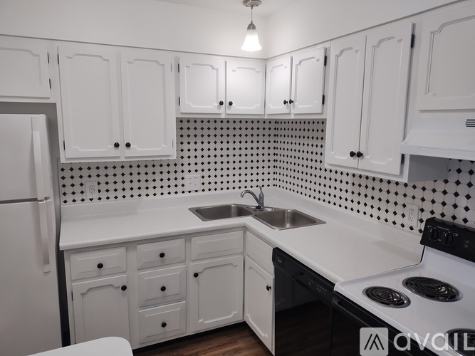A kitchen with white cabinets and a black and white tiled backsplash.