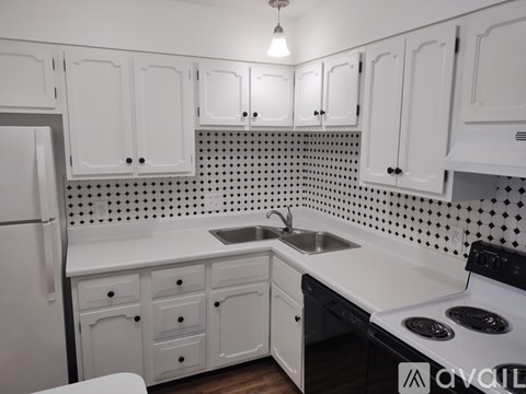 A kitchen with white cabinets and a black and white tiled backsplash.