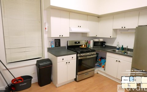 A kitchen with white cabinets and a black trash can.