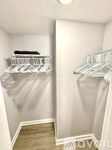 A white closet with two shelves and a black towel on the left.