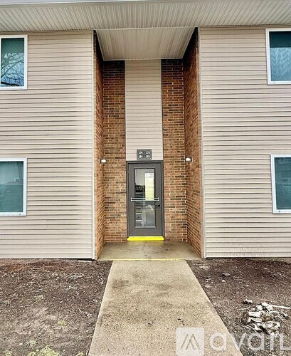The entrance to a building with a brick pillar and a glass door.