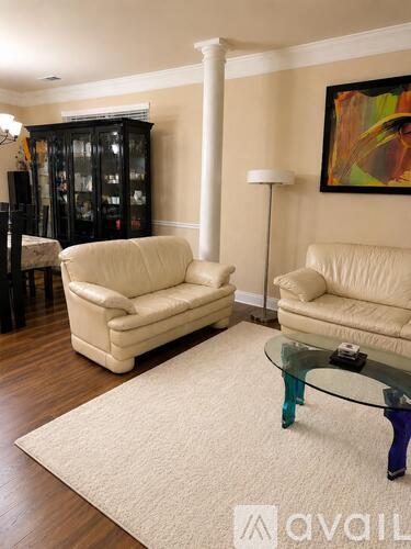 A living room with two cream sofas, a glass table and a painting on the wall.