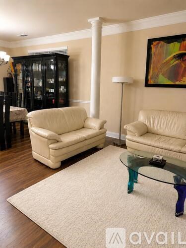A living room with two cream sofas, a glass table and a painting on the wall.