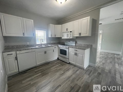 A kitchen with white cabinets and a wooden floor.