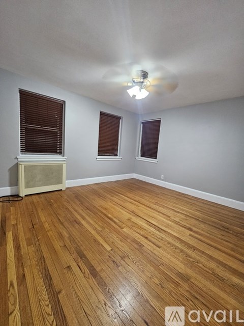 A room with wooden flooring and a window with blinds.