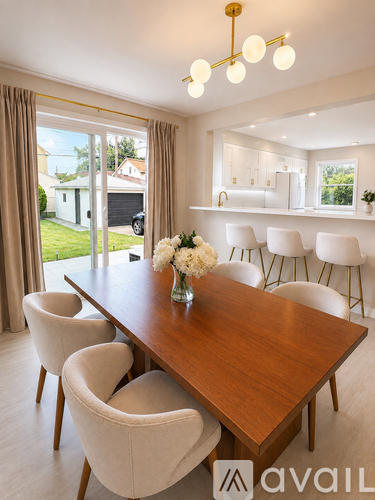 A dining room with a wooden table and white chairs.