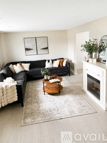 A living room with a black couch, a coffee table, and a fireplace.
