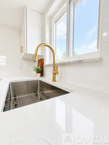 A kitchen with a stainless steel sink and a gold faucet.