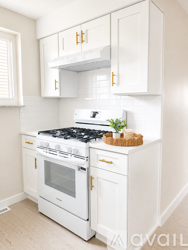 A white kitchen with a stove top oven and a white cabinet.