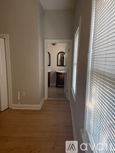 A hallway with a wooden floor and white walls.