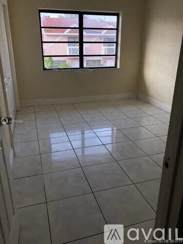 A room with a tiled floor and a window overlooking a building.