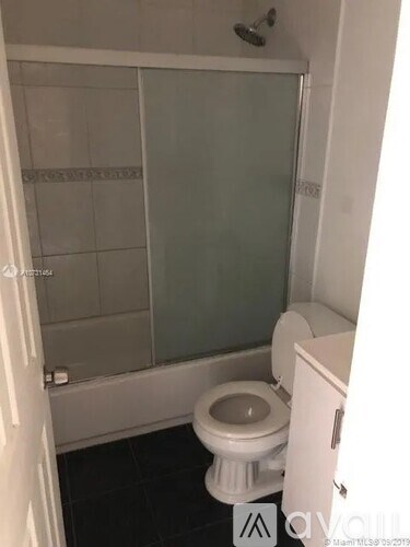 A white toilet in a small bathroom with a glass shower door.
