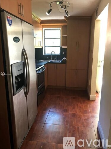 A kitchen with a stainless steel refrigerator and wooden floors.