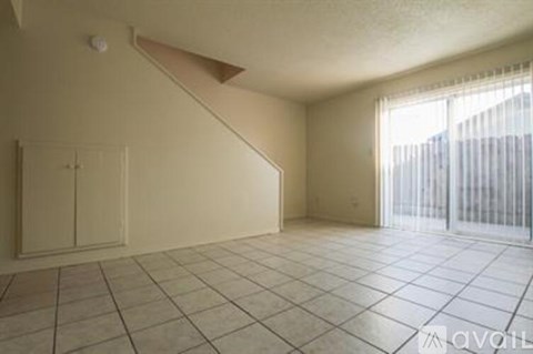 A room with a tiled floor and a window with blinds.