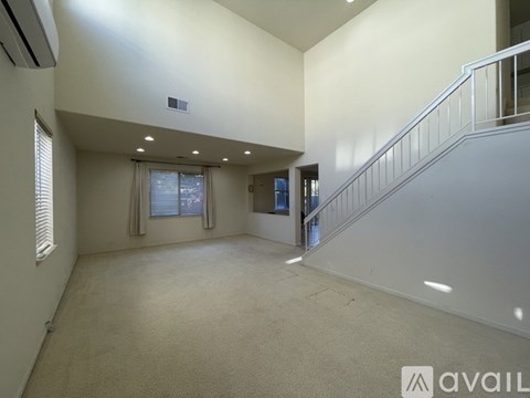 A spacious room with a staircase and a window with curtains.