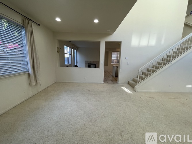 A spacious empty room with a staircase leading to the upper floor.