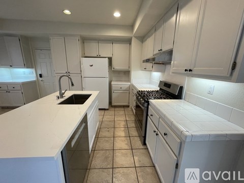 A kitchen with white cabinets and appliances.
