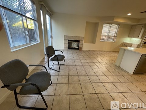 A living room with a fireplace and two chairs.