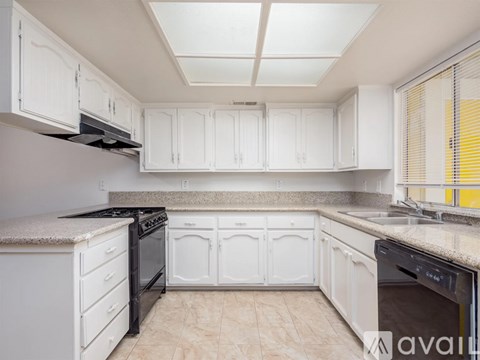 A kitchen with white cabinets and black appliances.