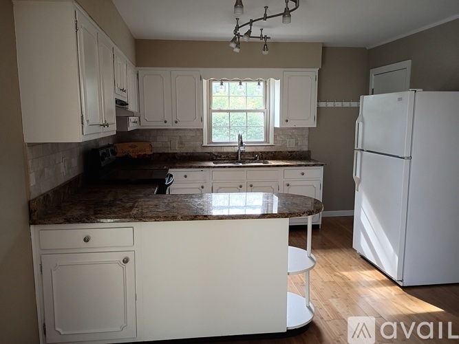 A kitchen with white cabinets and a marble countertop.
