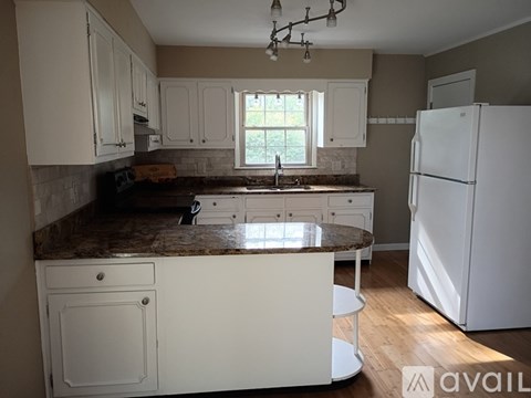 A kitchen with white cabinets and a marble countertop.
