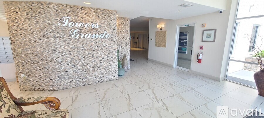 A lobby with a large marble wall and a chair.