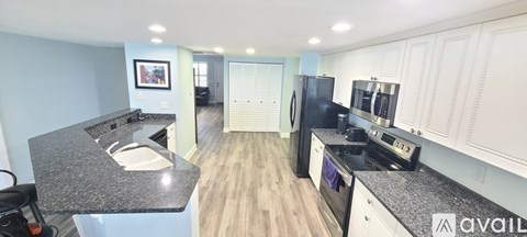 A kitchen with a black fridge and stove top oven.