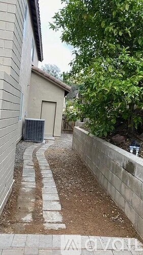 A concrete wall and a pathway leading to a building.