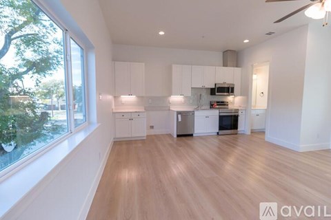 A spacious kitchen with white cabinets and a wooden floor.