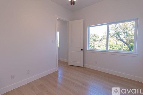 A room with a door and a window overlooking trees.