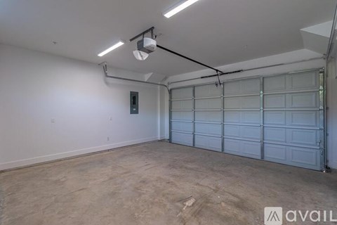 A spacious garage with a closed white door and a light on the ceiling.