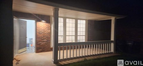 A patio area with a brick wall and a black railing.